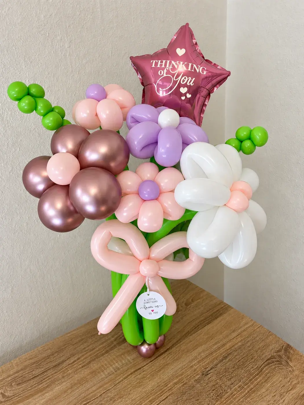 Hand twisted balloon flower bouquet in blush, rose gold and white with a foil star