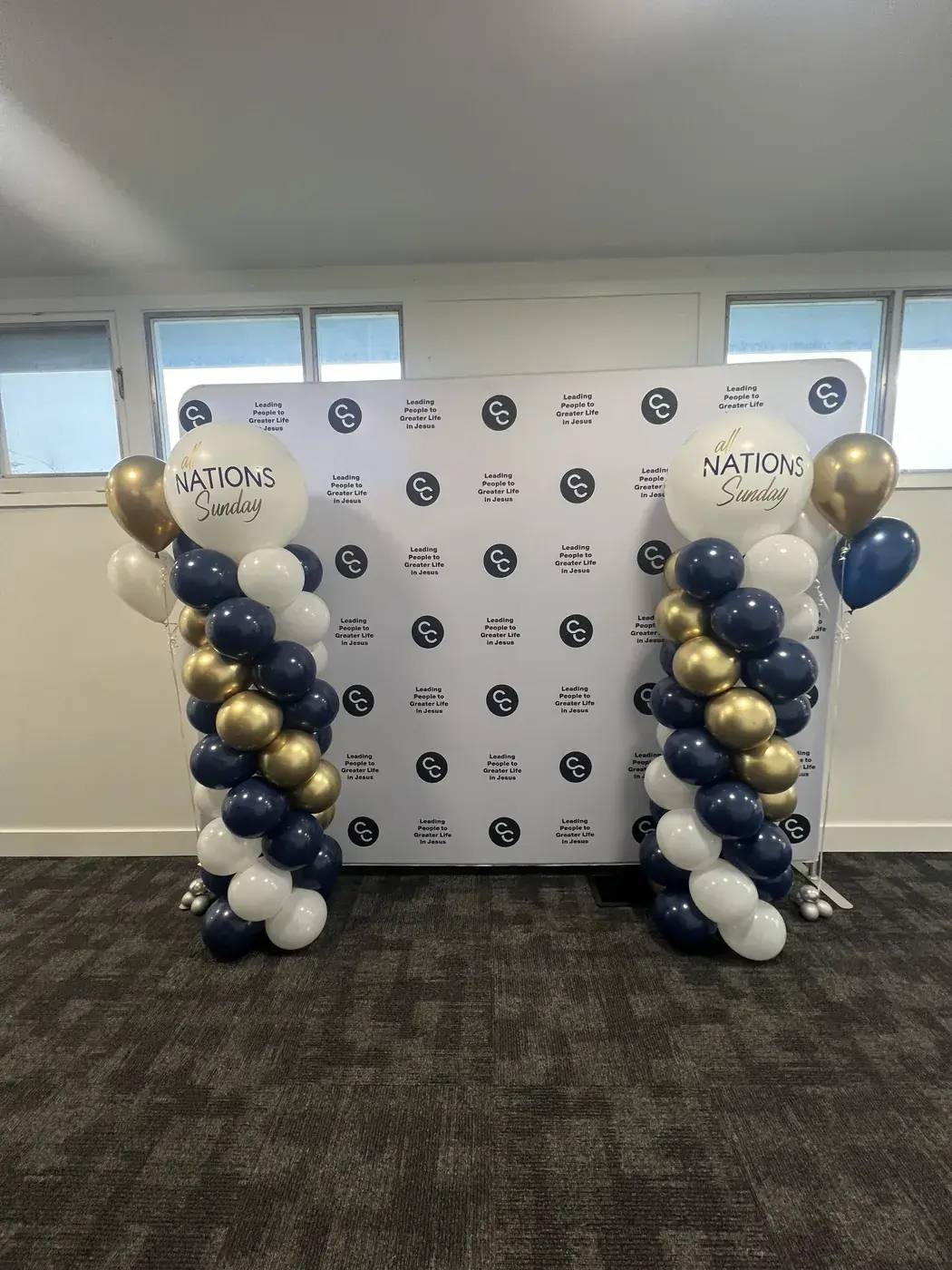Nations Sunday step and repeat with navy, gold and white balloon columns