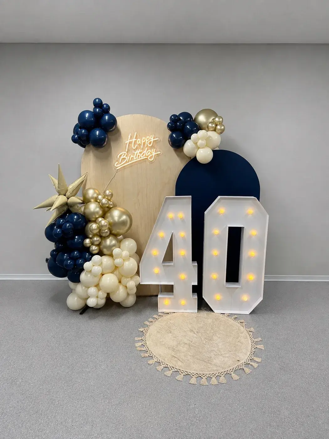 Navy and gold balloons around light-up 40 marquee numbers and a neon sign