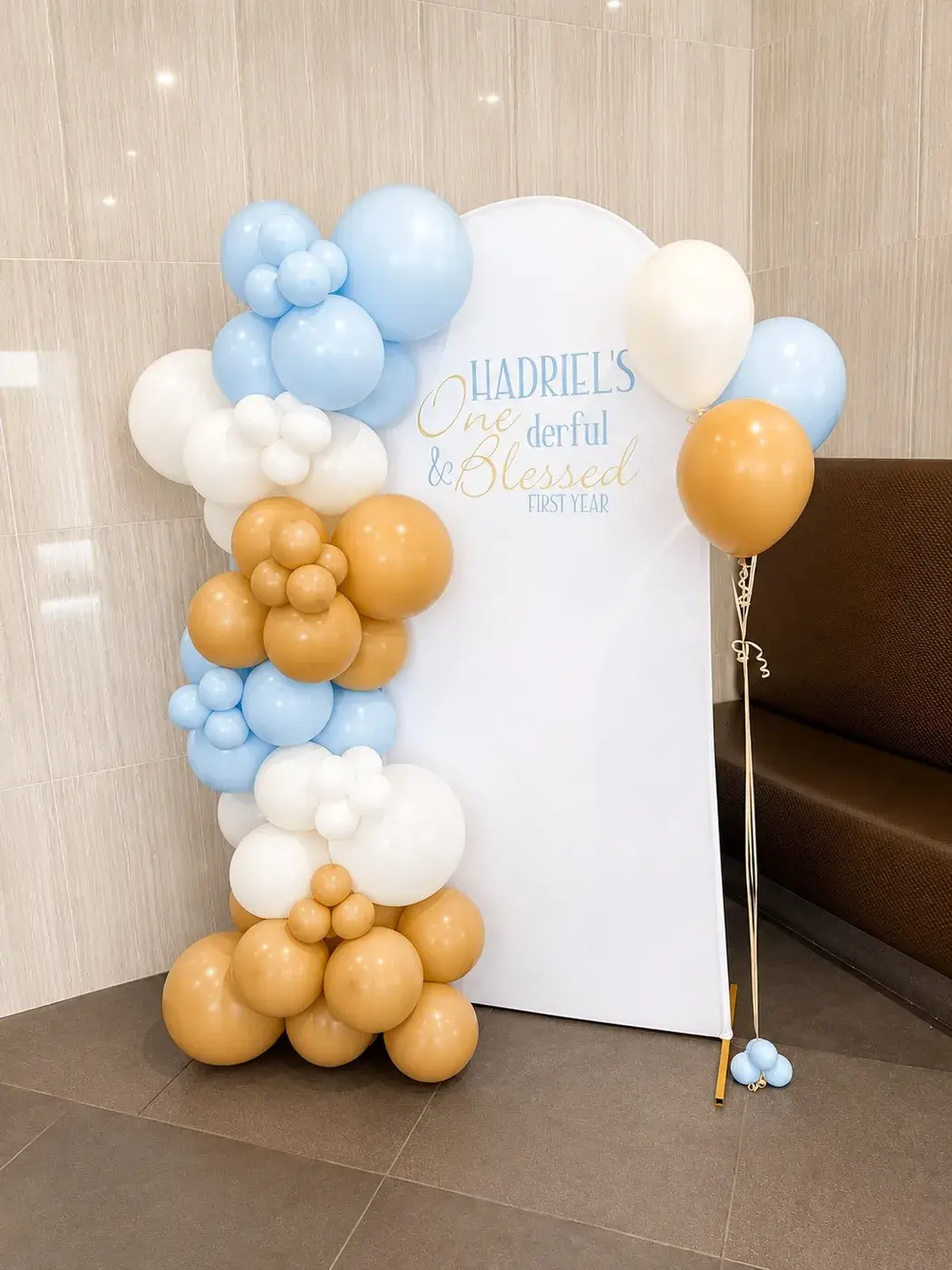 Blue, white and gold garland on a white arch for a first birthday