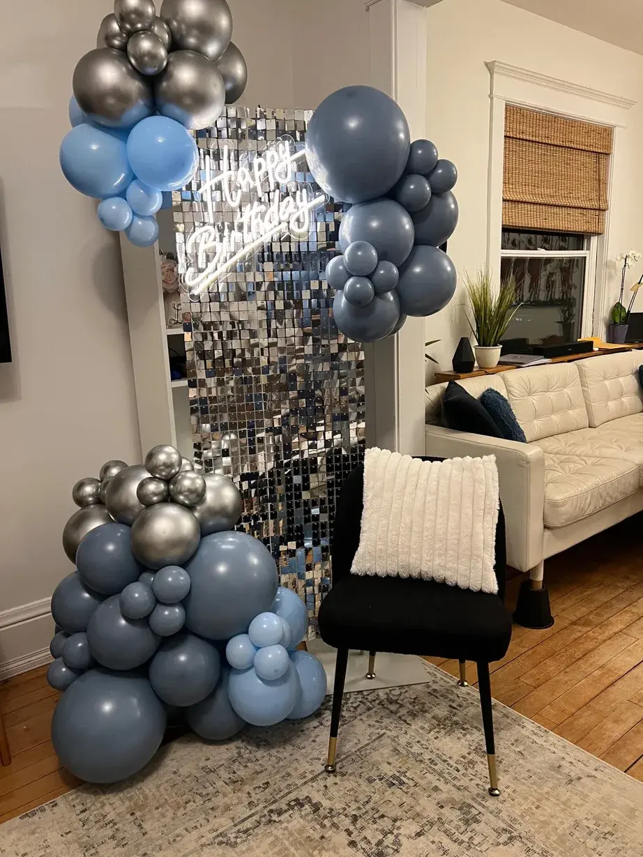 Blue, grey and silver garland against a disco shimmer wall with a neon birthday sign
