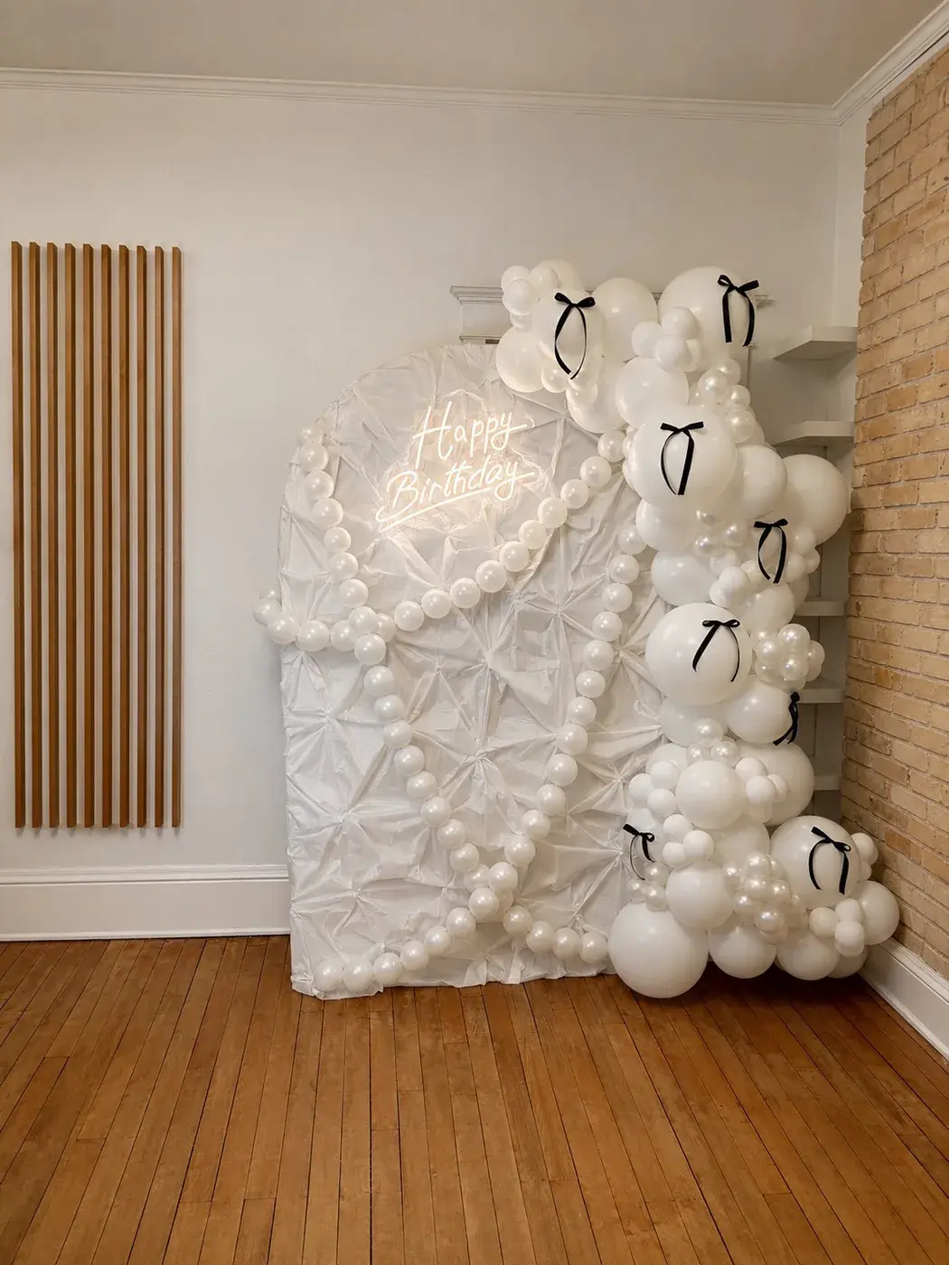 Ivory and pearl balloon backdrop finished with white bows